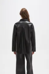 Sobrecamisa de cuero sintético en tono bordó oscuro, con cuello clásico, cierre frontal oculto y un bolsillo aplicado en el pecho. Presenta un corte holgado con mangas largas y puños rectos.