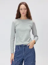 Remera de manga larga con cuello a la base, confeccionada en tejido de punto acanalado color beige. Presenta un logo bordado en el centro del pecho.