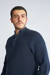 Sweater de tejido de punto acanalado en color negro, con cuello alto y cierre frontal parcial. Cuenta con mangas largas y un pequeño logo bordado en el ruedo.