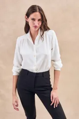 Blusa negra con cuello mao, calce al cuerpo y mangas 3/4 con puños abotonados. Cierre frontal con botones.