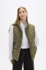 Chaleco acolchado de diseño capitoneado en color verde militar, con cuello alto, cierre frontal con botones a presión y bolsillos laterales con solapa y detalles en contraste.