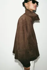 Chaqueta de tejido efecto ante color marrón, con cuello alto, cierre frontal con cremallera y botones a presión, manga larga y bolsillos de plastrón con solapa en el delantero.