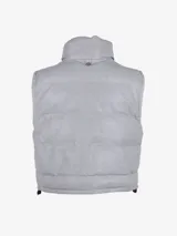 Chaleco puffer de cuero de cordero perforado en color gris. Presenta un diseño acolchado con cuello alto, cierre frontal de cremallera y ajuste en el bajo con cordones elásticos.