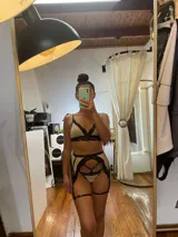 Conjunto de lencería de cuatro piezas compuesto por bralette, tanga, portaligas y ligas. Confeccionado en lycra beige con detalles de encaje negro en los bordes y tiras elásticas decorativas.