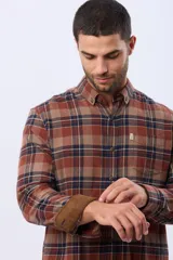 Camisa de viyela a cuadros en tonos marrón, azul marino y gris, con cuello clásico, cierre frontal con botones, mangas largas y un bolsillo en el pecho.