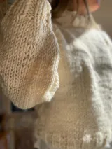 Sweater de lana color crema, tejido a mano con punto grueso.