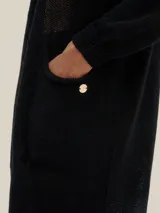 Cárdigan largo tejido en jersey color negro, con bolsillos delanteros y detalle de logo en cobre.