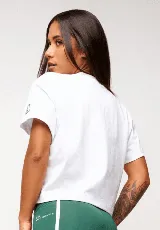 Remera blanca de algodón con corte crop, mangas cortas y estampado frontal con texto y logo en color gris.