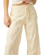 Pantalón de broderie color blanco, de pierna ancha, con cordón ajustable en la cintura y diseño calado con patrones geométricos.