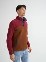 Buzo de polar color borgoña y marrón, con cuello alto con botones a presión y bolsillos laterales.