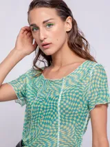 Top de mangas cortas con estampado geométrico en tonos verde y amarillo, con transparencias y costuras a la vista.