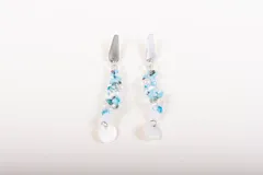 Par de caravanas colgantes con base metálica plateada y cuentas de cristal celeste, blanco y transparente.