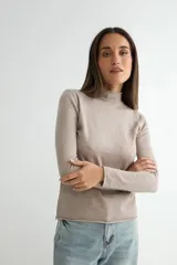Polera de tejido de punto fino en color beige, con cuello alto y mangas largas, de corte recto y ajuste cómodo.