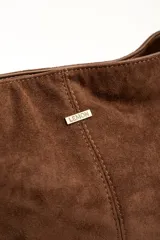 Cartera tipo bandolera de gamuza sintética color marrón, con asa larga decorada con nudos y detalles de herrajes metálicos dorados.