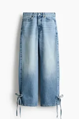 Jean tobillero barrel de tiro alto, confeccionado en denim de algodón rígido color celeste con efecto deslavado. Presenta diseño curvo en las piernas con volumen y tiras finas para atar en los bajos.