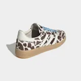 Championes Adidas Handball Spezial con diseño de estampado animal print tipo vaca en tonos marrón y blanco, con las icónicas tres tiras laterales en blanco, cordones celestes y suela de goma color caramelo.