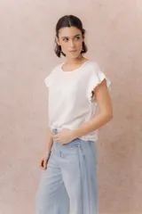Blusa blanca con escote redondo y mangas cortas con volados. Corte relajado y caída suave.