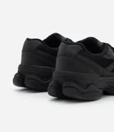 Championes estilo dad sneaker de diseño robusto, color negro, con suela alta y recortes laterales. Presentan cierre mediante cordones y una estructura que combina paneles de malla y material sintético.