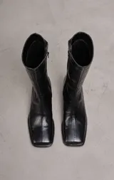 Bota de cuero negra, de caña media, punta cuadrada y taco bajo forrado.