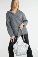 Bolso tote plateado, tipo shopper, con diseño acolchado. Forrado internamente en color negro.