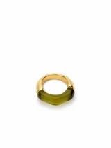 Anillo de diseño mixto que combina una banda de metal dorado con una sección frontal de resina translúcida en color verde oliva.
