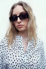 Blusa blanca con estampado floral negro, cuello mao y mangas largas con puños abotonados.