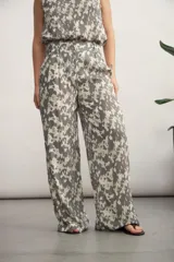 Pantalón de corte recto y tiro alto, confeccionado en tela fluida con estampado abstracto en tonos negro y beige.