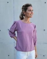 Blusa de algodón color rosa, con cuello redondo, mangas tres cuartos abullonadas con costuras decorativas visibles y corte recto.