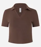 Blusa de cuello polo y manga corta, confeccionada en tejido rib de algodón con elastano. Presenta un diseño ajustado al cuerpo con escote en V y textura acanalada.