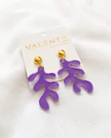 Par de aros colgantes con forma de hoja abstracta color lila y base dorada.