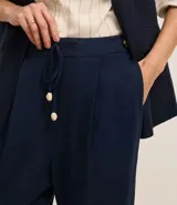 Pantalón celeste de corte recto, confeccionado en tejido de lino y viscosa. Presenta cintura elástica con lazo ajustable, bolsillos laterales y pliegues frontales.