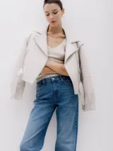 Chaqueta corta estilo biker color beige, confeccionada en piel sintética. Presenta cierre asimétrico frontal, bolsillo con cierre a la vista y bolsillo con solapa, cinturón con hebilla en la cintura.
