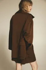 Trench color marrón confeccionado en mezcla de lyocell y lino. Cuello solapa y manga larga. Bolsillos con solapa en delantero. Cierre frontal con botones a presión.