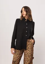 Camisa negra de cuello redondo con frunces y mangas largas con puños abiertos.