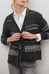 Sacon de tejido de punto grueso con diseño de ochos y rayas horizontales en contraste. Presenta cuello en V, cierre frontal con botones oscuros y mangas largas con puños acanalados.