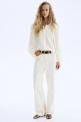 Blusa de manga globo larga color crema, con cuello redondo fruncido y botones ocultos en la parte delantera. Presenta un bajo redondeado.