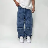Pantalón de jean azul, corte holgado, con múltiples bolsillos tipo cargo y texto bordado en la pierna.