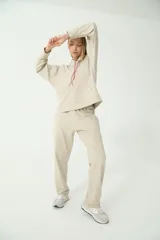 Buzo hoodie color arena, de rústico, con capucha y cordón de ajuste en salmón y verde. Tiene moldería oversize y etiqueta de la marca en la manga derecha con logo Basset 00'S.