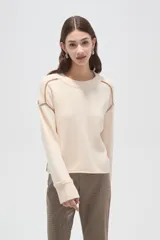 Sweater de algodón color natural, de corte holgado y cuello redondo. Presenta detalles de costuras decorativas con bordado en los hombros y puños acanalados.