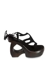 Sandalias negras de gamuza con plataforma de madera y tiras que se atan al tobillo.