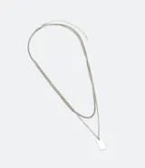 Collar doble dorado con cadena fina y dije rectangular.