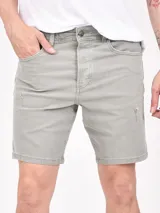 Bermuda de gabardina color oliva, con diseño de cinco bolsillos, cierre frontal con botón y detalles de desgaste sutiles.