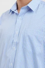 Camisa celeste con rayas verticales blancas, de manga larga con puños abotonados y cuello clásico.