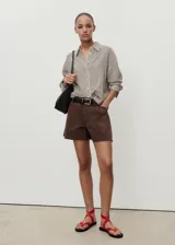 Short de algodón estilo denim, color marrón, con tiro medio, pinzas delanteras, cuatro bolsillos y bajo deshilachado.