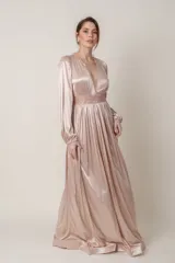 Vestido largo de satén color champagne, con escote en V profundo y mangas largas abullonadas con puños elásticos. Presenta apliques bordados con lentejuelas en el escote y la cintura.