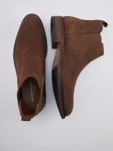 Bota Chelsea de gamuza gris con elásticos laterales, suela de goma marrón y tirador trasero.