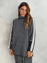 Sweater de punto con patrón de espiga en tonos beige y marrón, cuello alto, mangas largas con detalles en naranja y puños marrones.