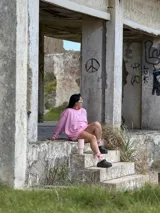 Buzo deportivo oversize color rosa, con cuello redondo y costuras expuestas en rojo. Presenta un pequeño bordado de una letra 'K' en el pecho.