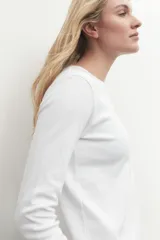 Remera de manga larga color blanco, con cuello redondo y calce al cuerpo.