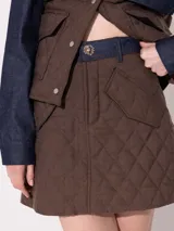 Minifalda marrón con diseño acolchado a cuadros y cinturón de denim azul.